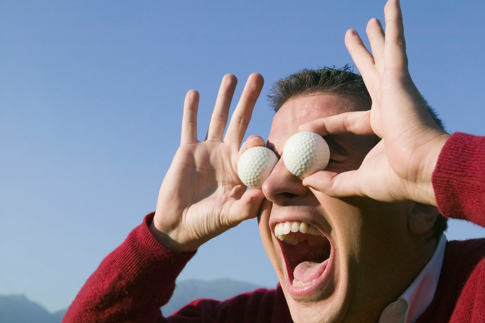 Golfer holding golf balls over eyes