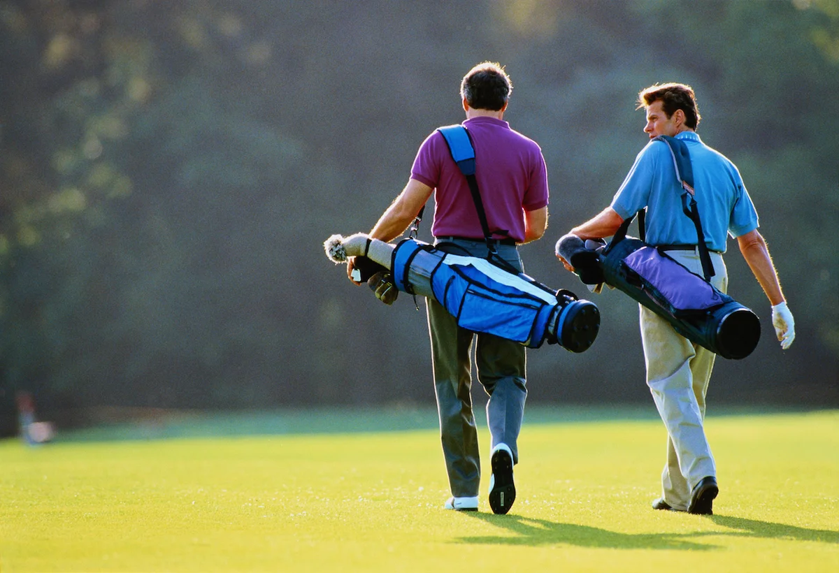 Golfers carrying clubs on course