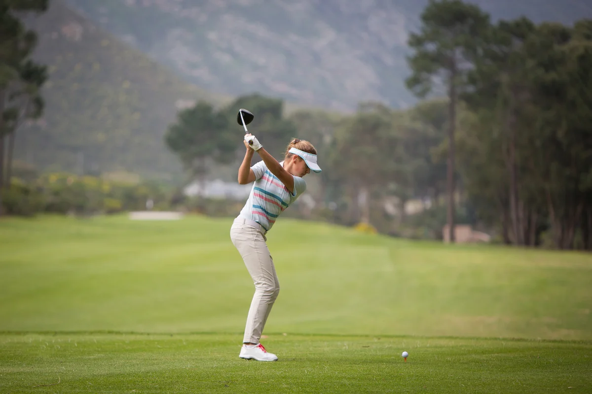 woman swinging golf club on course