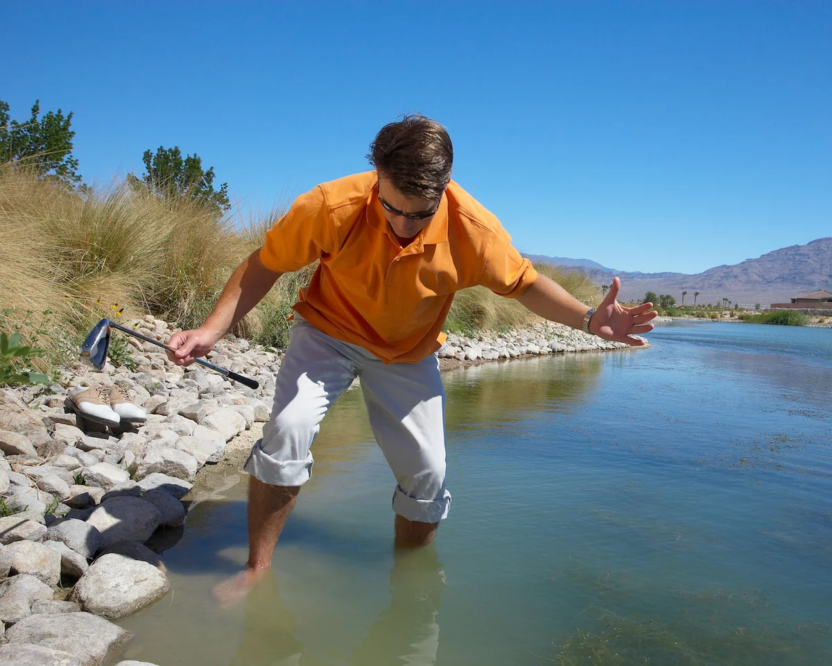 Golfer looking for ball in water