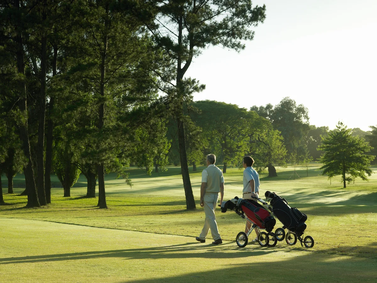 golfers pulling push carts on course