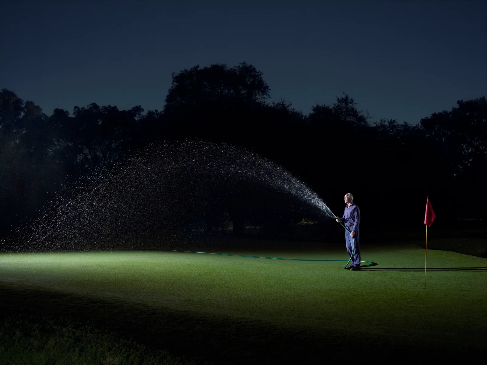 Golf superintendent watering green at night