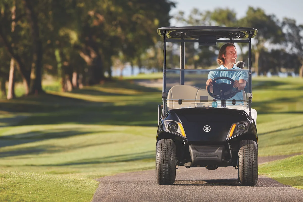 man driving Yamaha cart on course