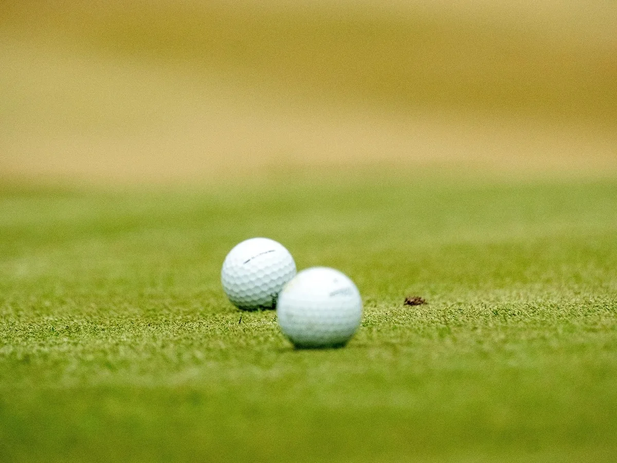 Two golf balls at rest on the putting green