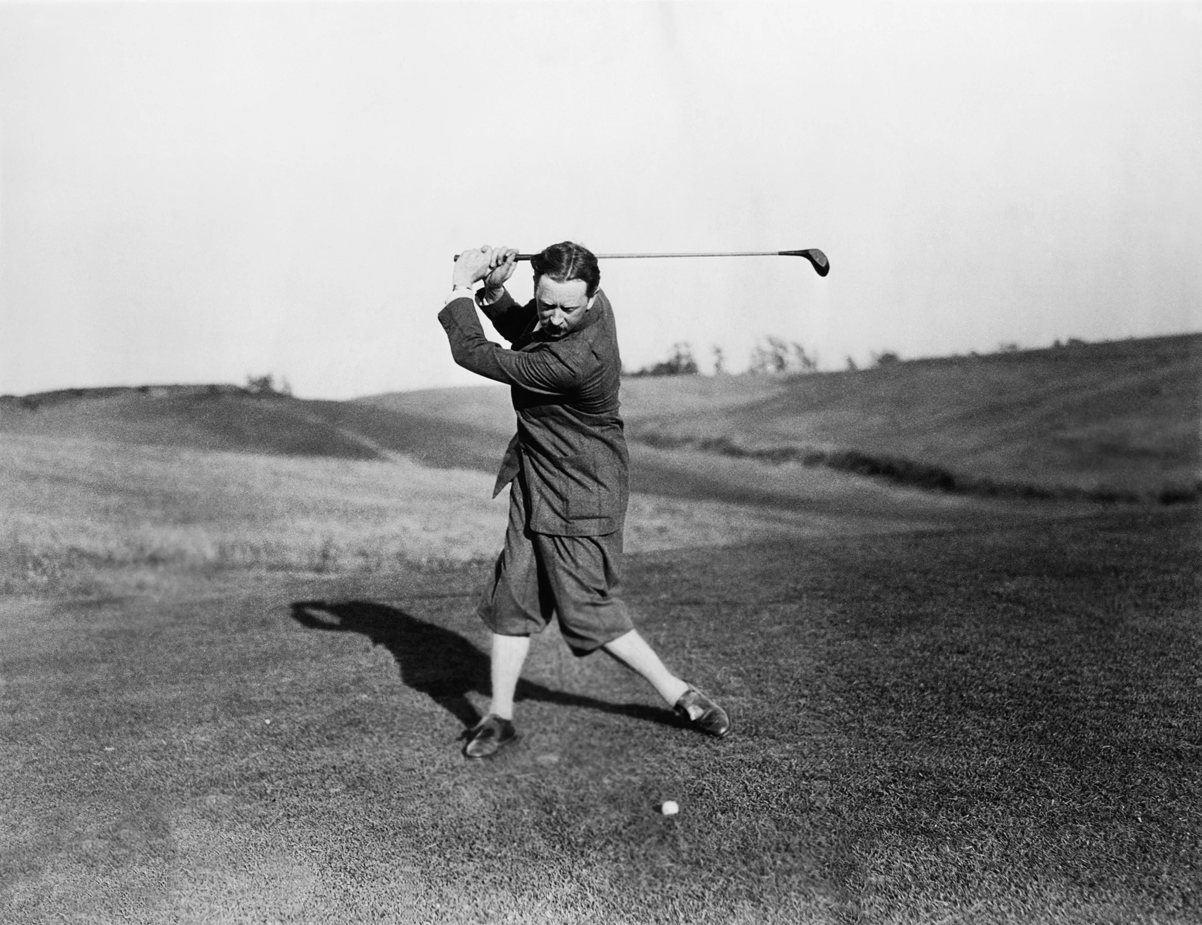 Old time photo of a man playing golf