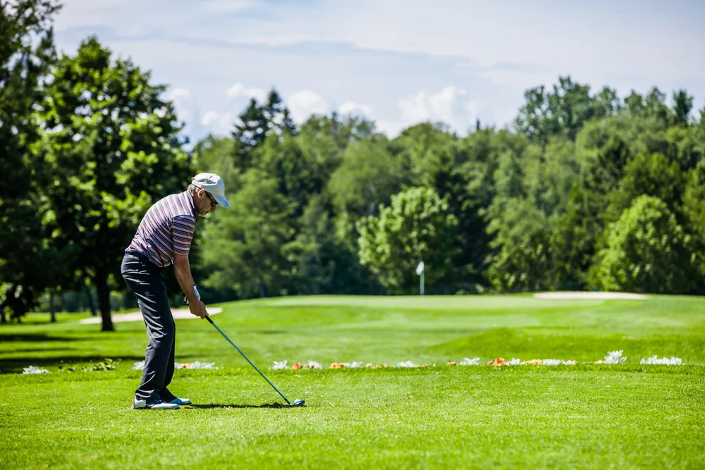 Mature golfer hitting a hybrid golf club