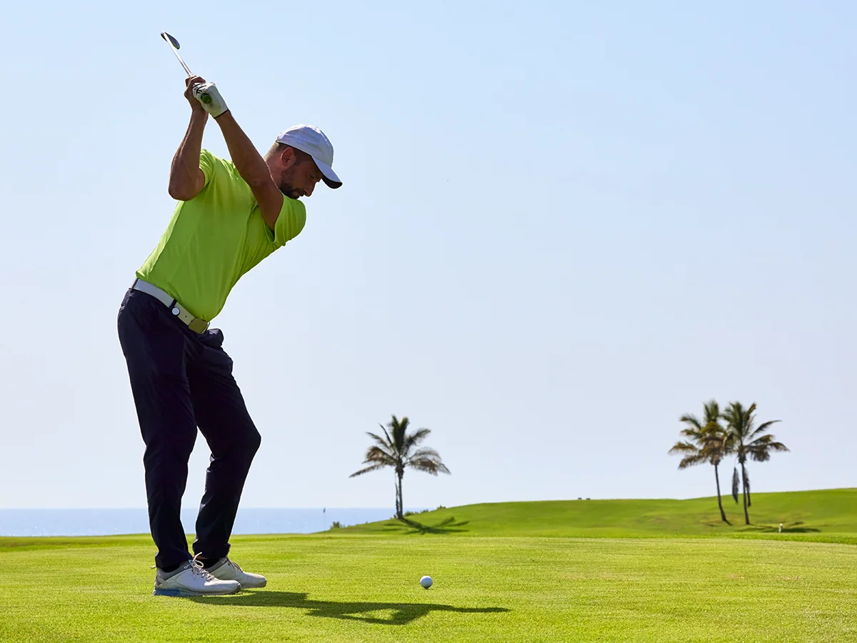 Golfer at the top of his swing with iron